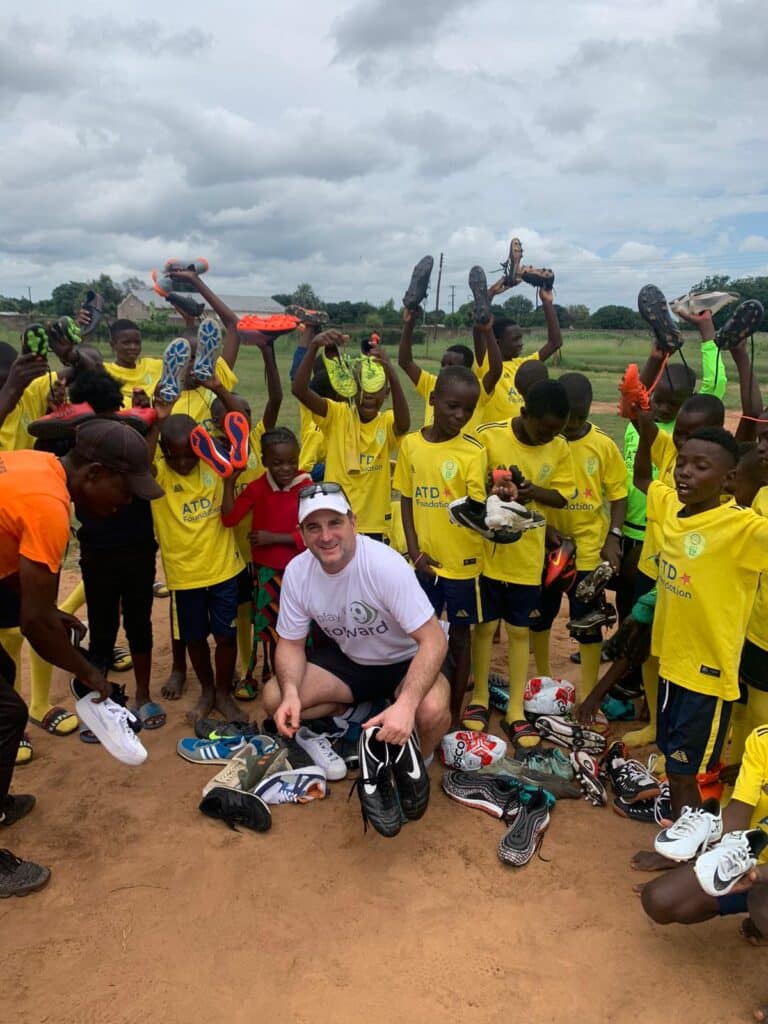 Oliver Brendon giving children donated football boots.