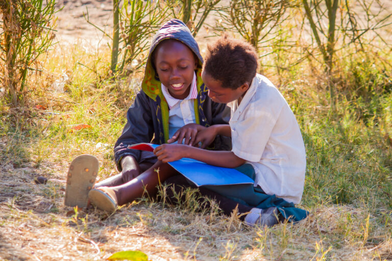 Two Zambian children reading a book.