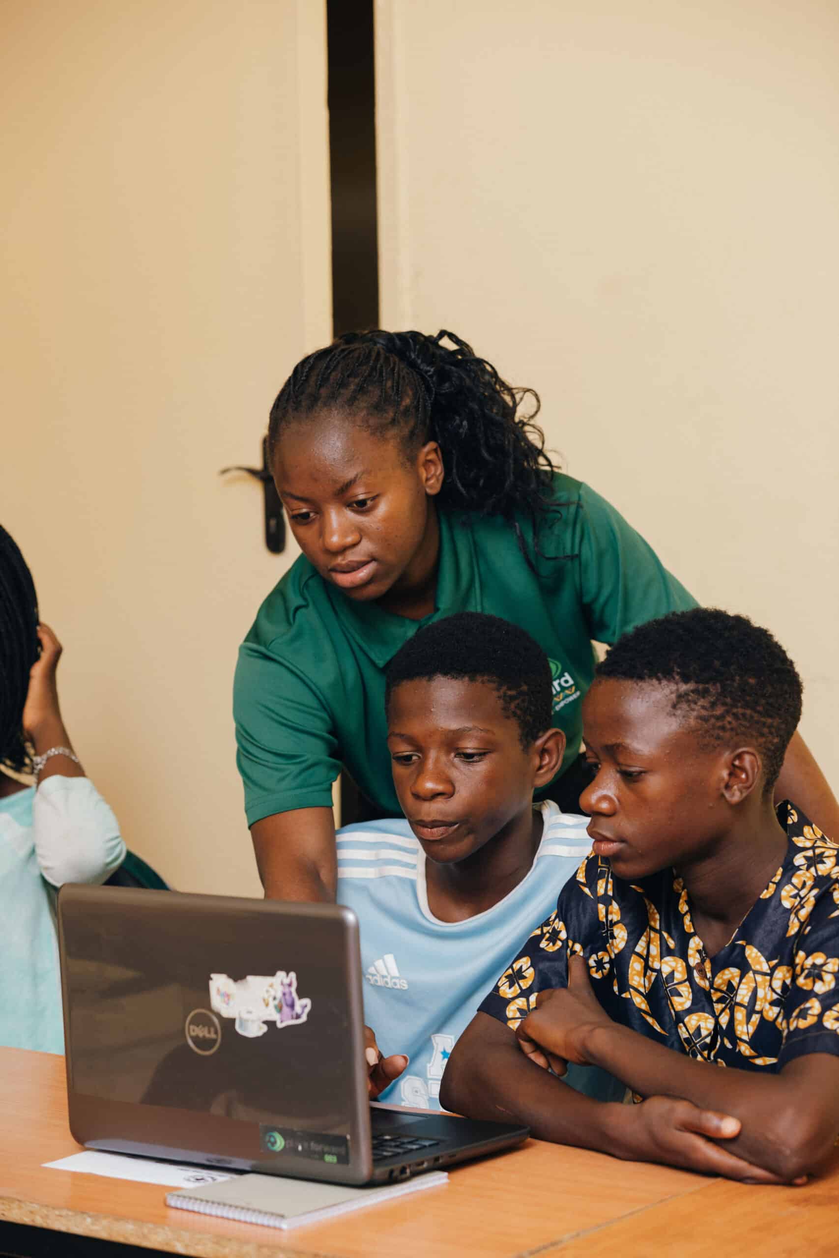 A project officer helping children in a digital skills learning session.