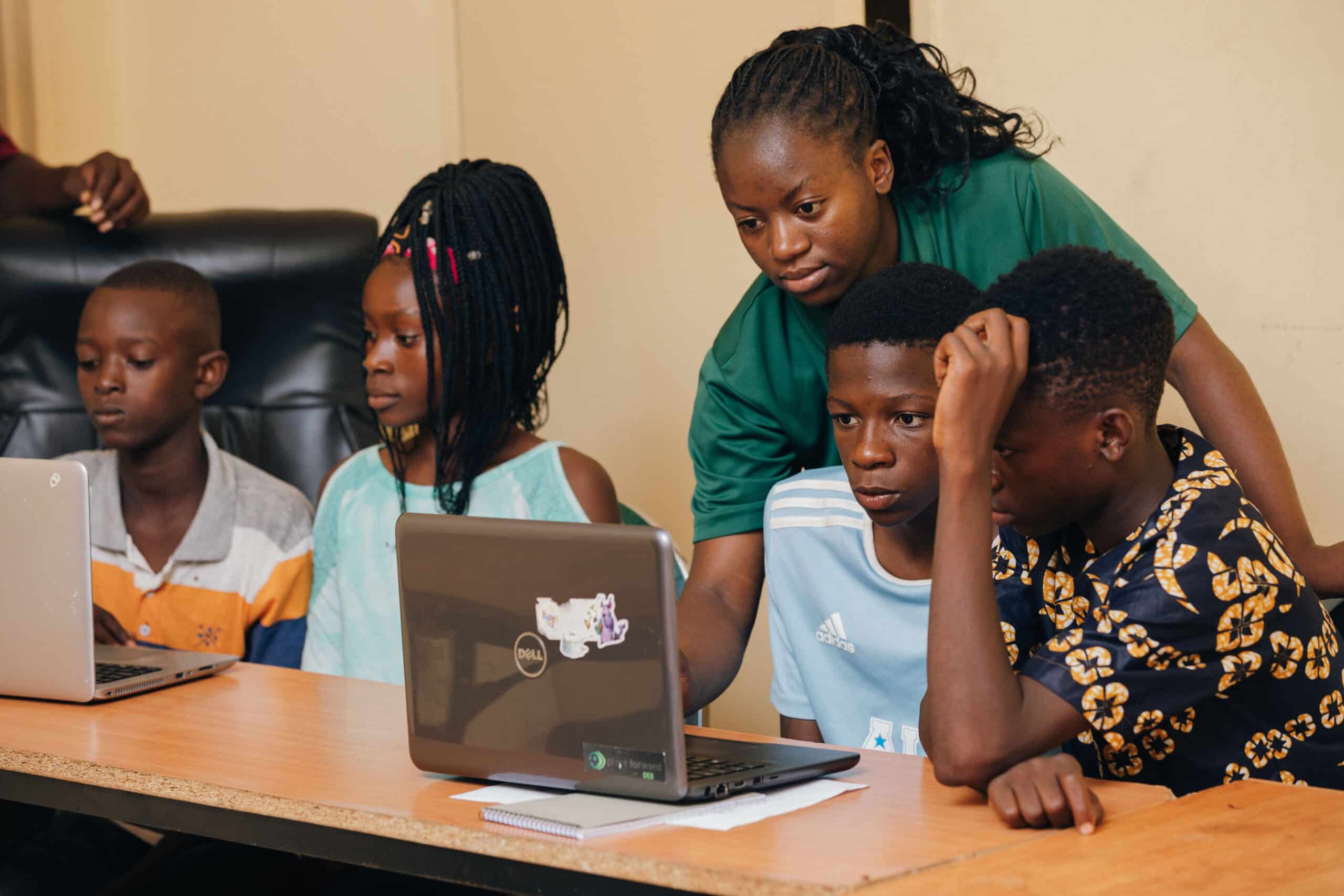 A project officer helping children in a digital skills learning session.